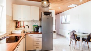 A modern kitchen with white cabinets, a stainless steel refrigerator, and a dining area with a table and chairs. - Beautiful apartment in Marcana with WiFi (Marcana)