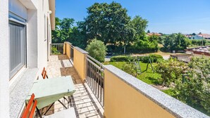 A balcony with a table and chairs, overlooking a garden with a swing set and a car in the background. - Beautiful apartment in Marcana with WiFi (Marcana)
