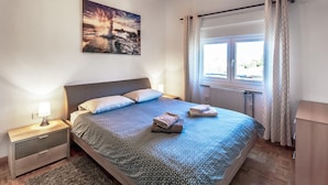 A bedroom with a bed, a nightstand, a lamp, a window with curtains, and a painting on the wall. - Beautiful apartment in Marcana with WiFi (Marcana)