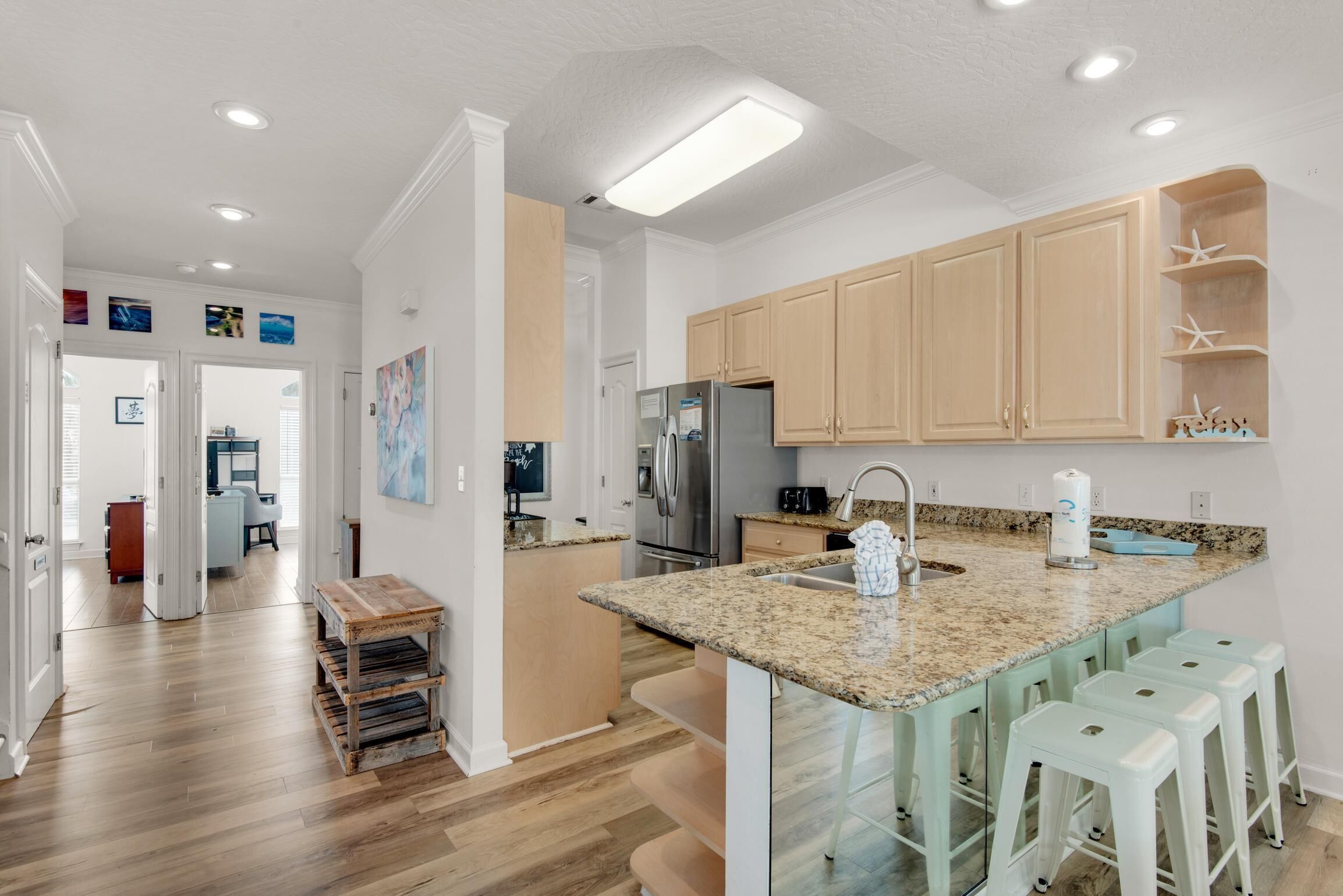 A modern kitchen with granite countertops, wooden cabinets, and a stainless steel refrigerator.
