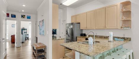 A modern kitchen with granite countertops, wooden cabinets, and a stainless steel refrigerator.