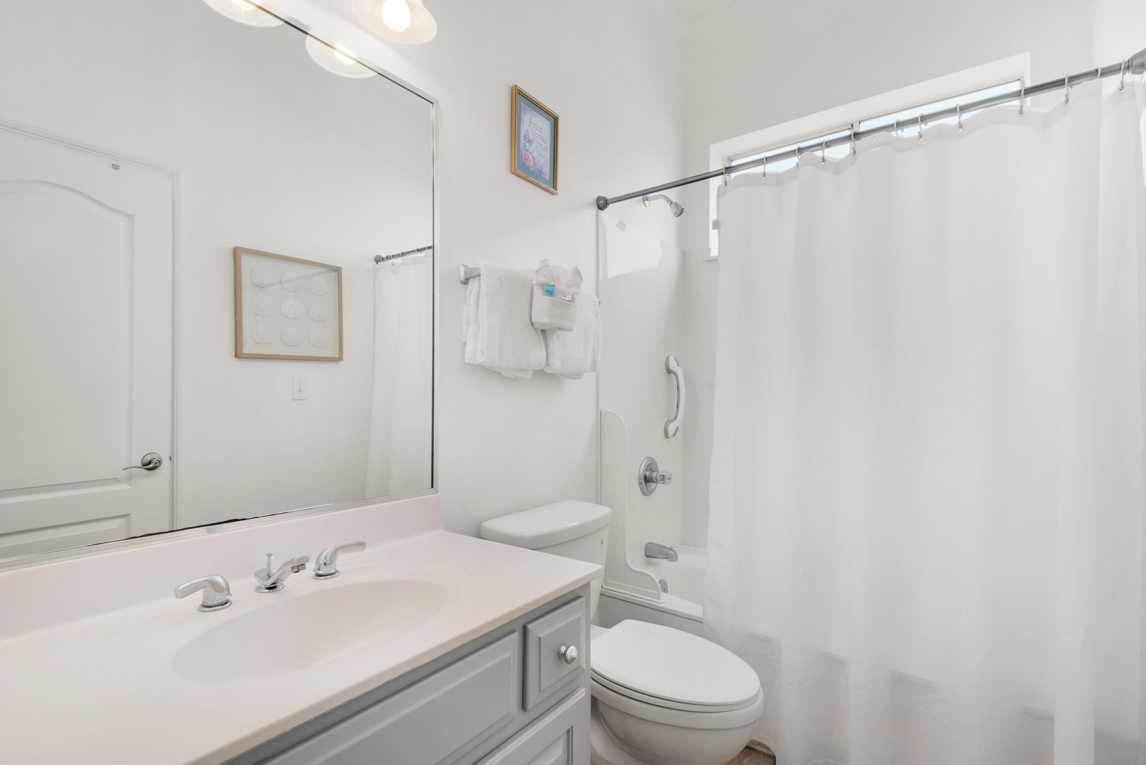 Une salle de bain avec un lavabo blanc, des toilettes et un rideau de douche.