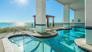 An indoor swimming pool with a view of the ocean, surrounded by white pillars and a pergola. - Majestic Beach Towers 1-2113 (Panama City Beach)