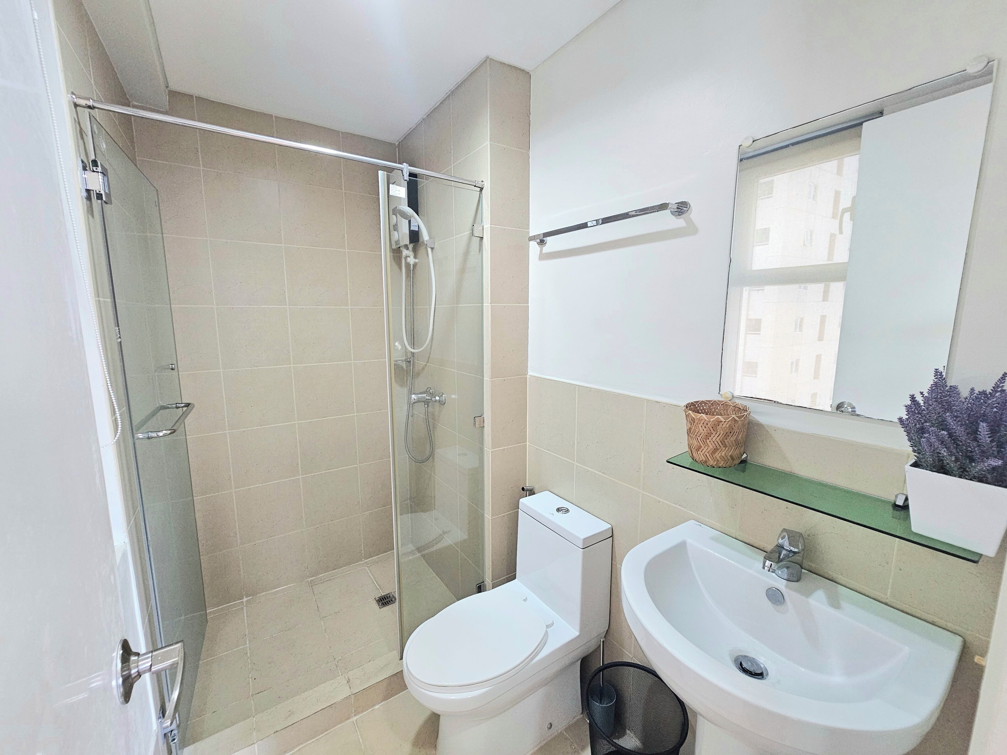 Un baño moderno con ducha de vidrio, inodoro blanco, lavamanos y espejo.