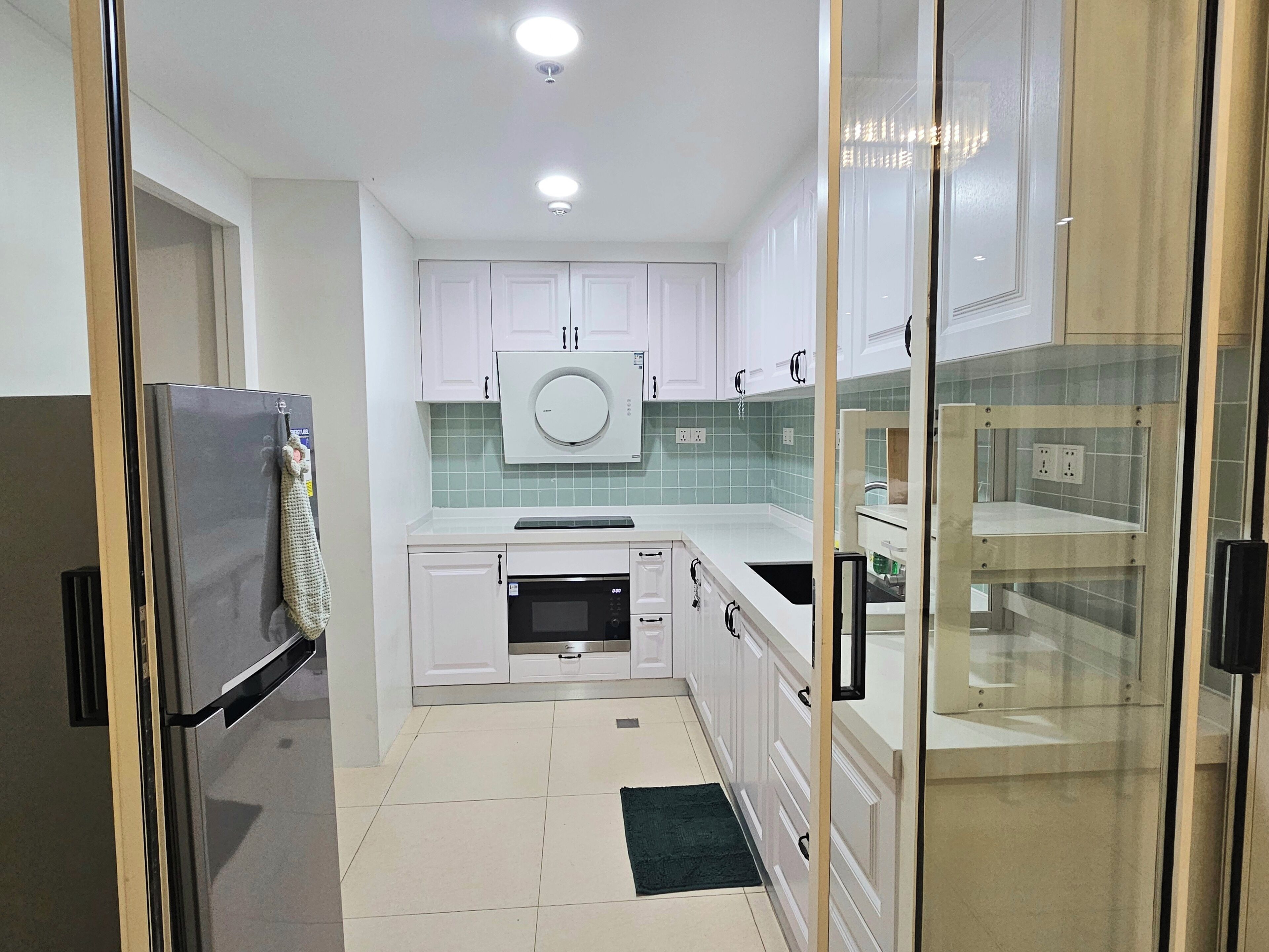 A compact kitchen with white cabinets, a microwave, and a refrigerator.