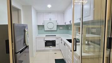A compact kitchen with white cabinets, a microwave, and a refrigerator.