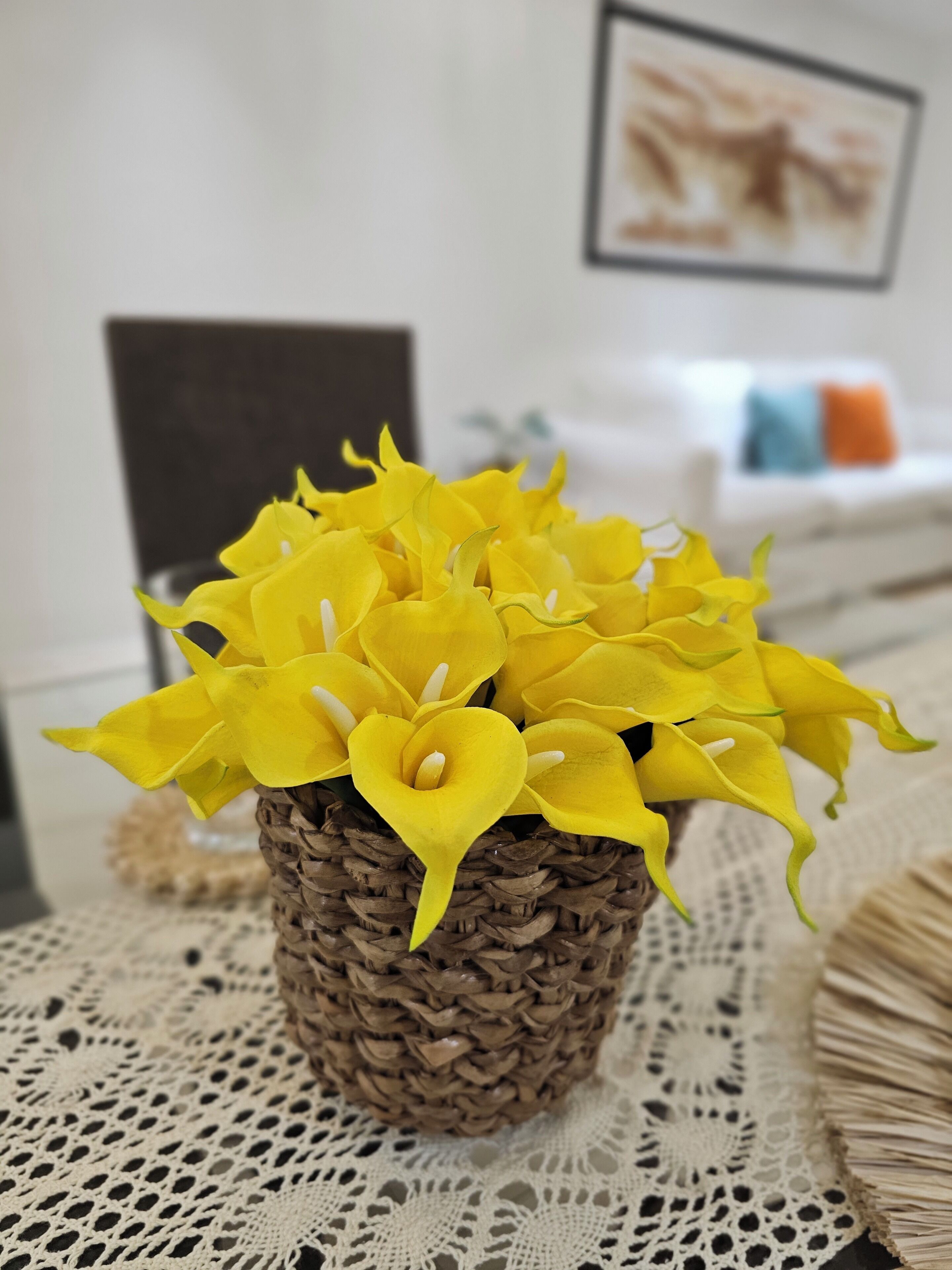 A wicker basket containing yellow flowers on a lace tablecloth.