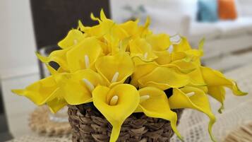 A wicker basket containing yellow flowers on a lace tablecloth.