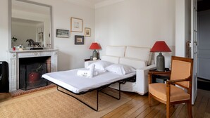 A bedroom with a bed, a chair, a fireplace, and two lamps. - Appartement Apalta - Welkeys (Paris)