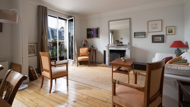 A living room with wooden flooring, a fireplace, a dining table, and a sofa. - Appartement Apalta - Welkeys (Paris)