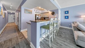 Eine moderne Küche mit weißen Schränken, einer Granitabdeckung und einer Uhr an der Wand.