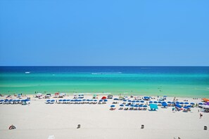 A wide beach with numerous umbrellas and sun loungers, a clear blue sky, and calm turquoise waters. - Long Beach Resort 2 603 (Panama City Beach)