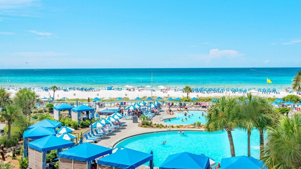 A resort with a large pool area, multiple lounge chairs, and umbrellas. - Edgewater Tower 1-305 (Panama City Beach)