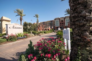 A hotel entrance with a sign reading 'Azure,' a paved walkway, and a garden with pink flowers. - Azure #407 (Fort Walton Beach)
