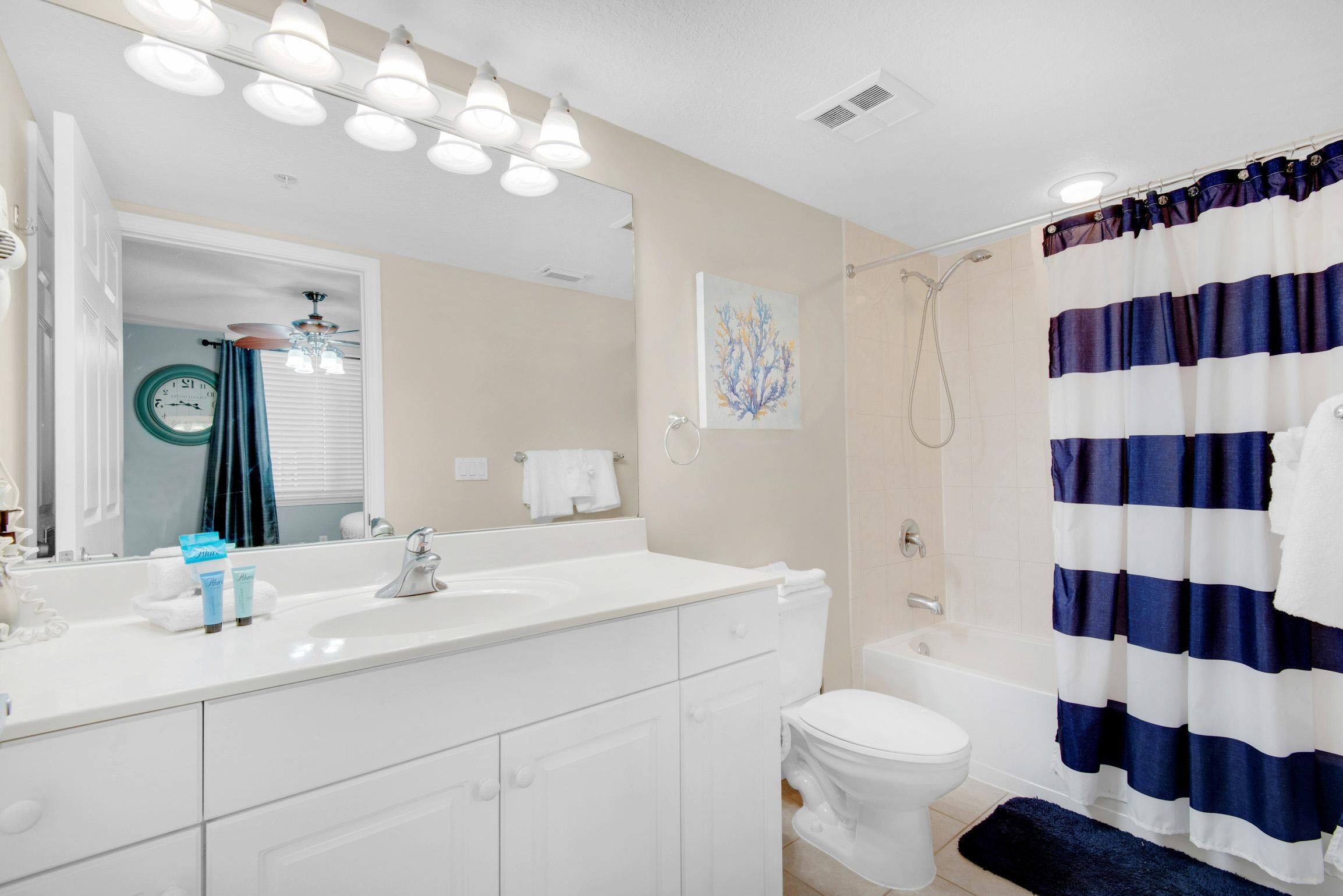 A bathroom with a white sink, mirror, and toilet. There is a shower curtain and a towel rack.