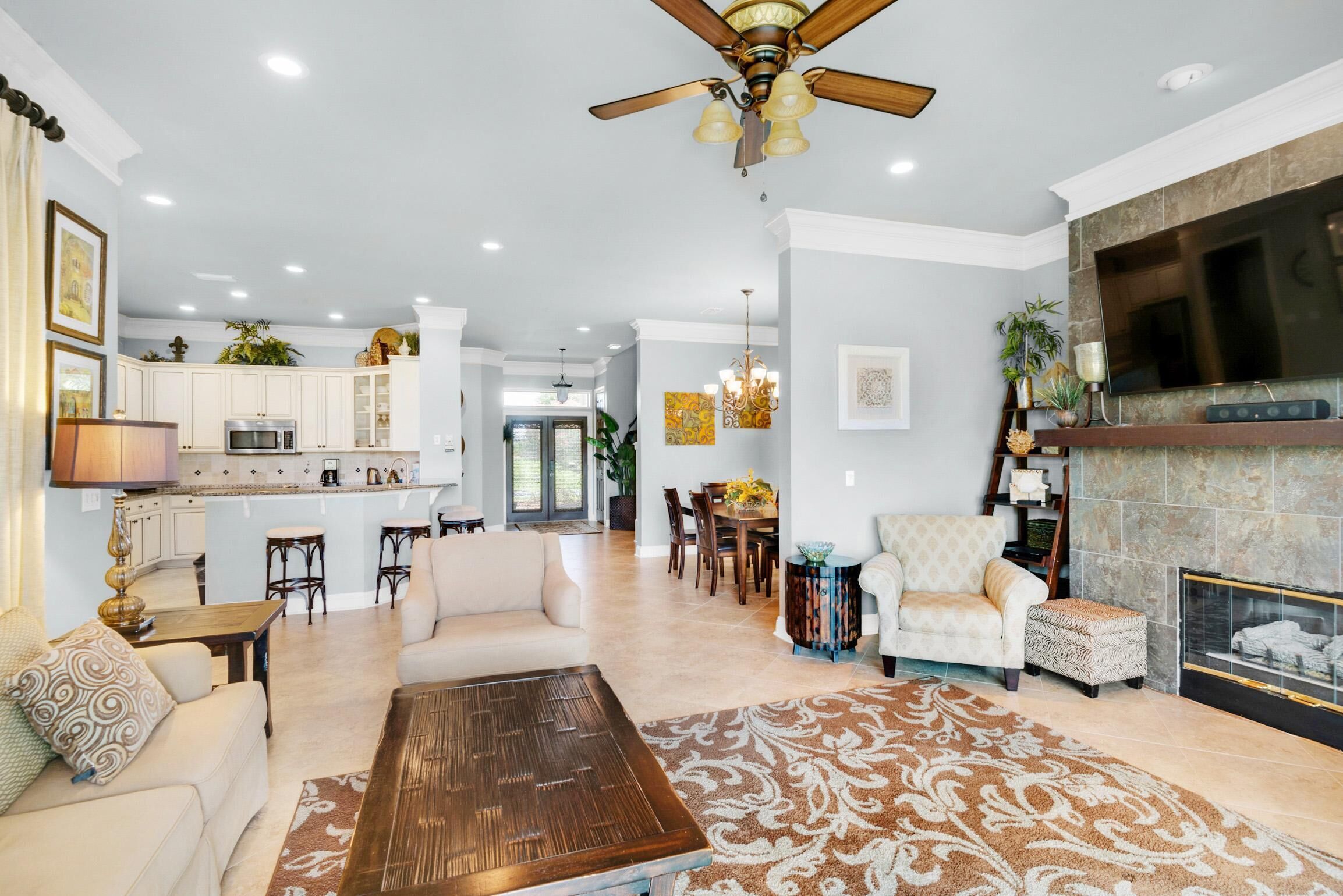 A spacious living area with a fireplace, a dining table, and a kitchen in the background.