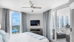 Une chambre à coucher comprenant un lit, une télévision, un ventilateur de plafond et un balcon aménagé avec du mobilier d’extérieur.