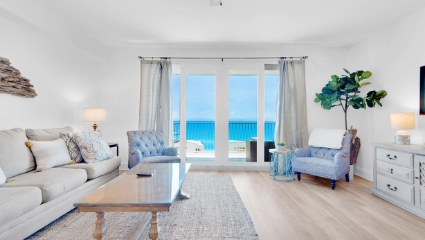 A spacious living room with a large window, a ceiling fan, and a view of the ocean. - Laketown Wharf 1714 (Panama City Beach)
