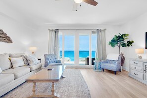 A spacious living room with a large window, a ceiling fan, and a view of the ocean. - Laketown Wharf 1714 (Panama City Beach)