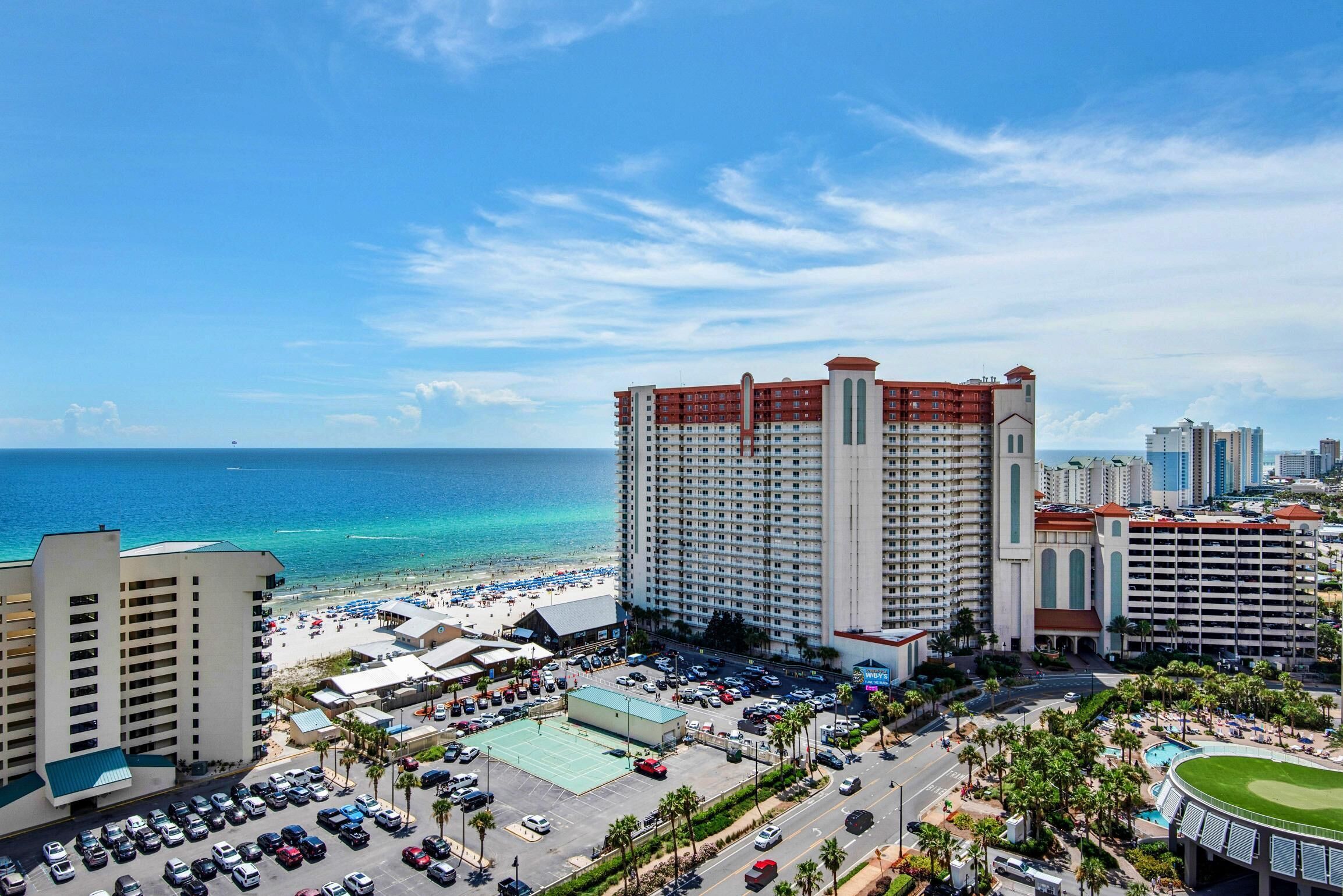 A hotel with a beach view, multiple parking lots, and a pool area.