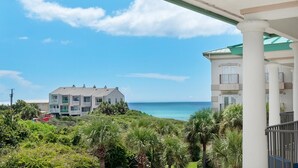 A beachfront property with a view of the ocean, a covered patio area, and lush greenery. - Legacy 506- The Coastal Gem (Santa Rosa Beach)