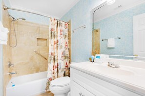 Een badkamer met een bad, toilet en douche.