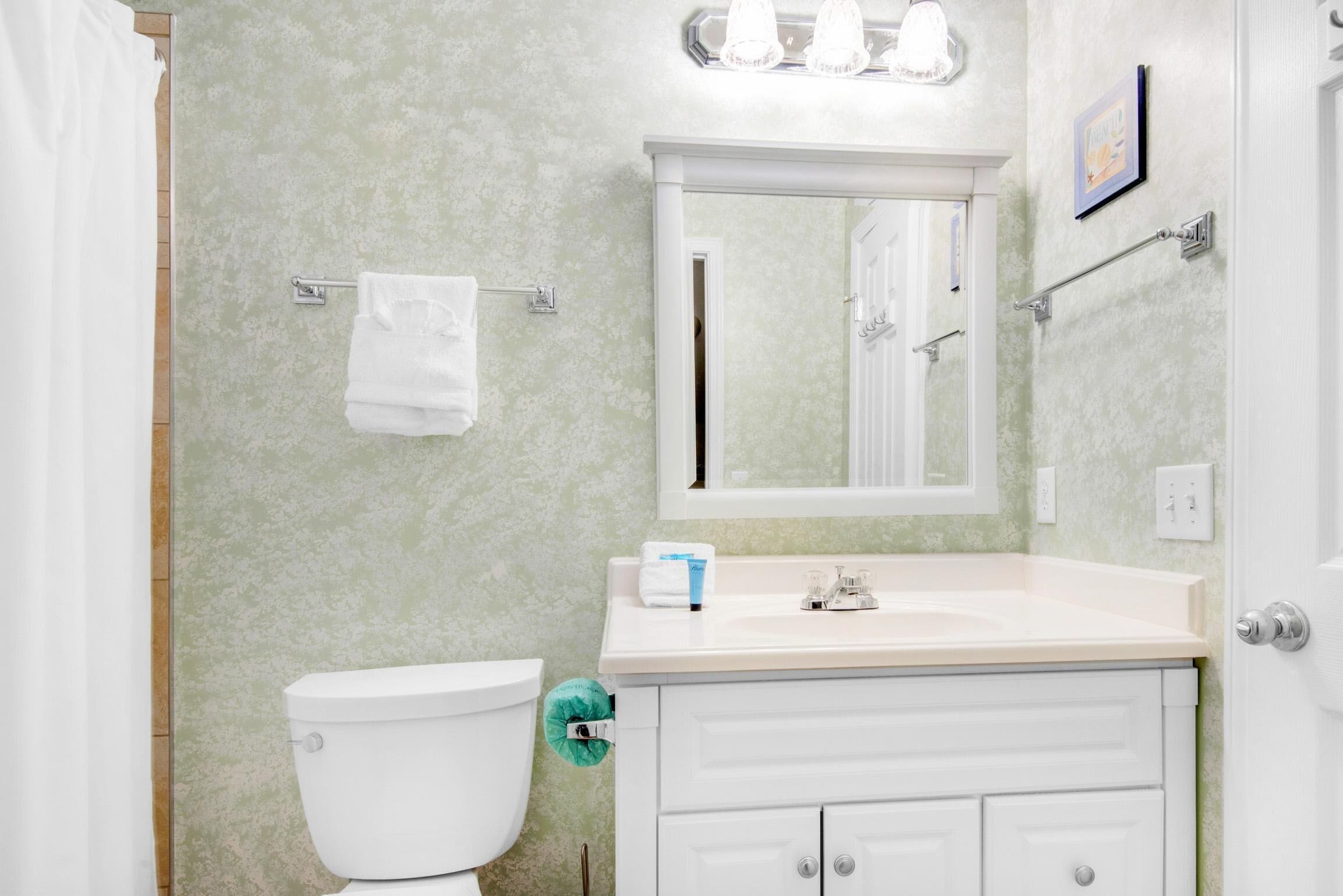 A bathroom with a toilet, sink, and mirror.