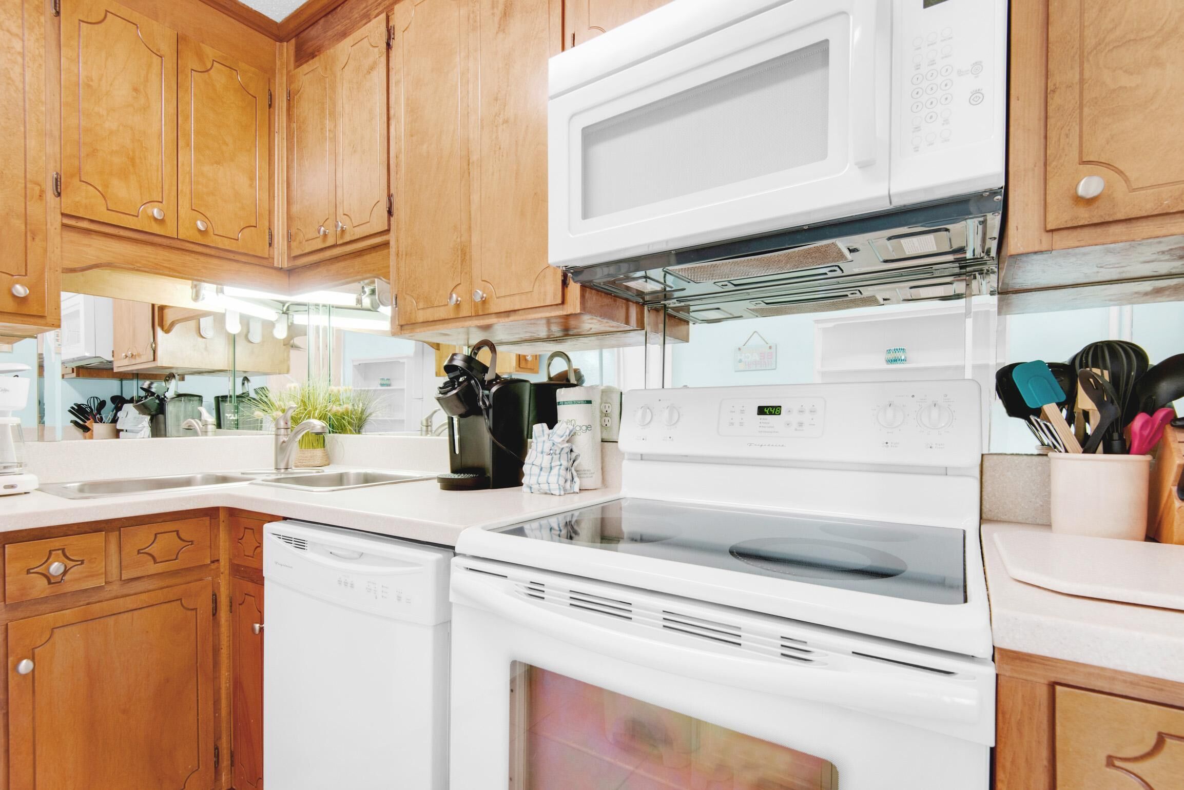 A kitchen with wooden cabinets, a microwave, an oven, and a dishwasher.
