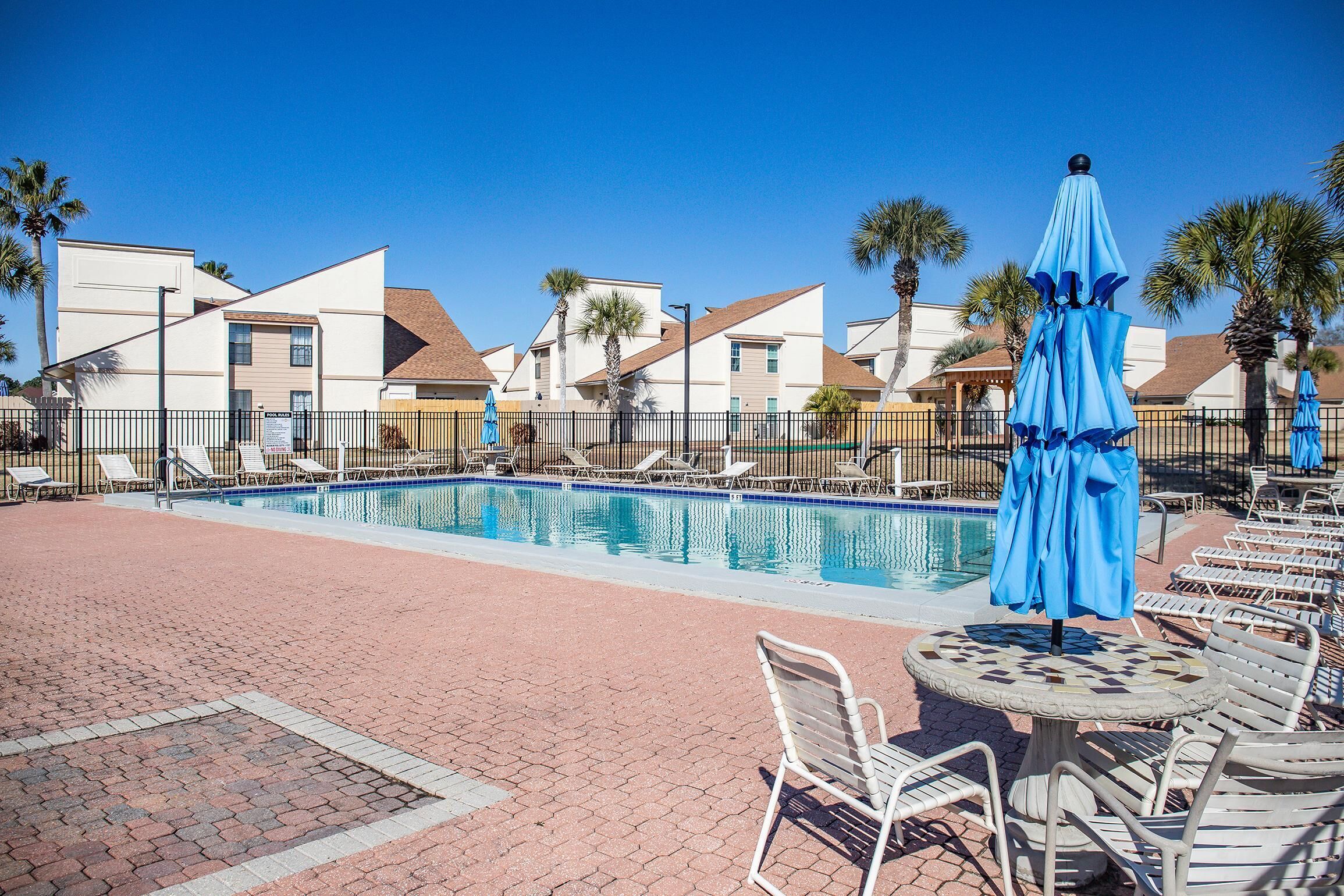 A pool area with lounge chairs and umbrellas, surrounded by buildings with a modern architectural style.