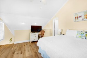 Een slaapkamer met een bed, een bureau, een stoel, een televisie en een raam.