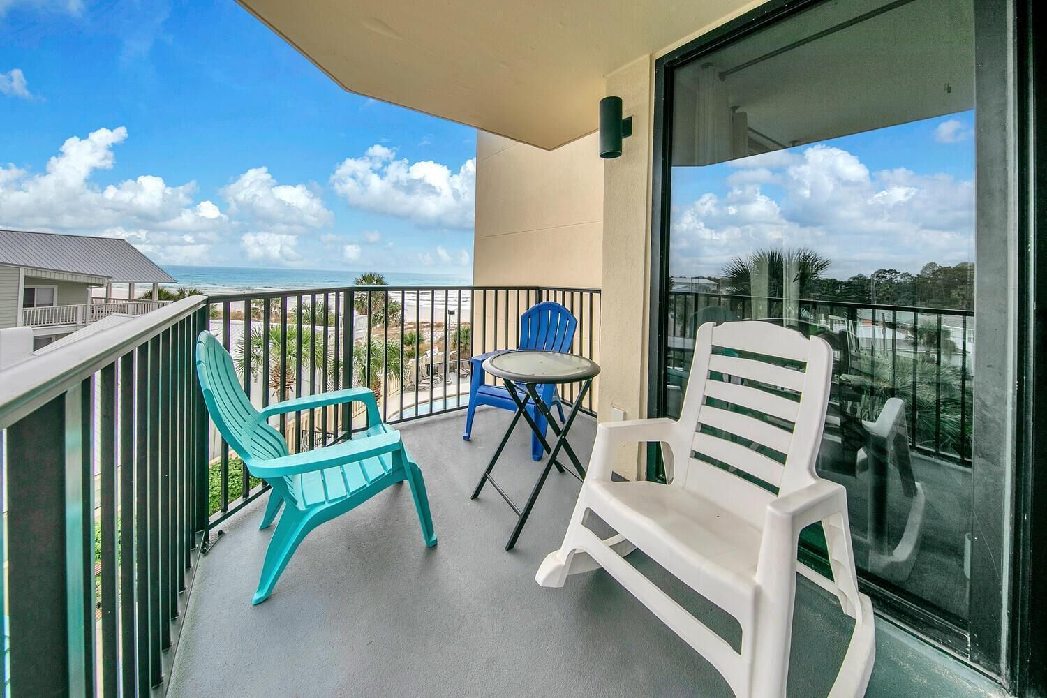 Ein Balkon mit zwei Stühlen und einem kleinen Tisch, der Blick auf einen Strand und Palmen bietet.