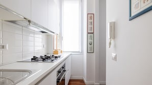 Una cocina moderna con gabinetes blancos, una campana extractora de acero inoxidable y un ventanal que proporciona luz natural.
