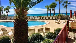 Ein Poolbereich mit Liegestühlen und Palmen, mit Blick auf einen Strand.