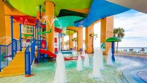 A water park with slides, a pool, and a beach area with lounge chairs.