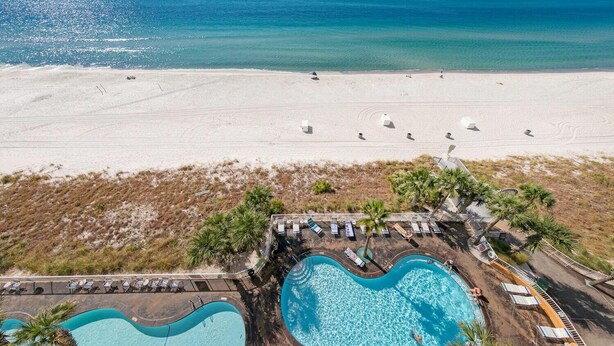 A resort with two swimming pools, a beach, and a view of the ocean.