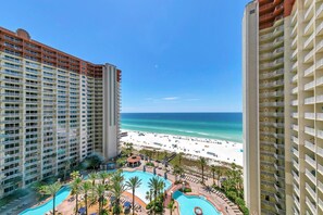 A hotel with a pool area, beach view, and multiple balconies. - Shores of Panama 1212 (Panama City Beach)