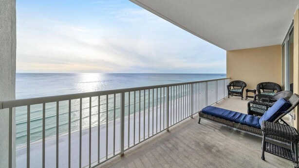 A balcony with a view of the ocean, a seating area with two chairs and a sofa, and a railing.