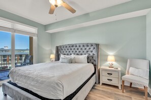 Ein Schlafzimmer mit einem großen Bett, einem Nachttisch, einem Sessel und einem Balkon mit Blick.