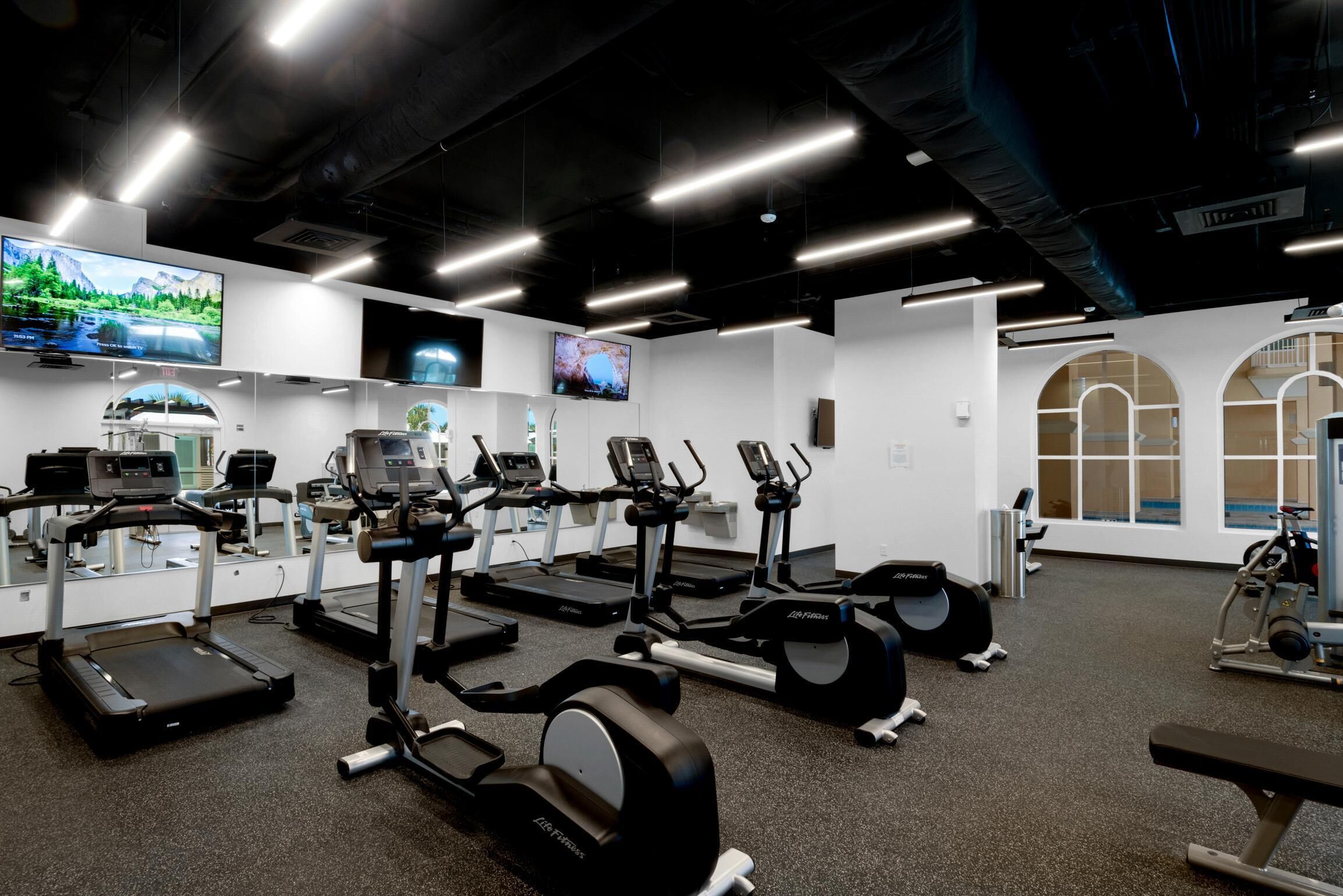 A gym with treadmills, elliptical machines, and weight equipment.