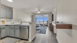 A modern kitchen with grey cabinets, a dishwasher, and a wooden countertop. - Calypso 3-504 (Panama City Beach)