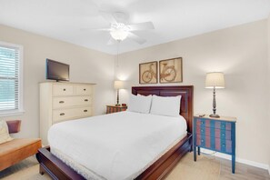 Cozy retreat with a large bed, dresser, and nightstand, featuring a ceiling fan and two wall-mounted lamps.