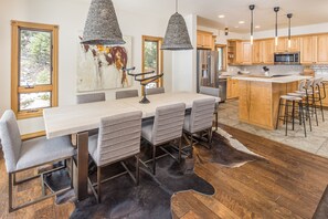 A modern kitchen with wooden cabinets, a stainless steel refrigerator, and a large island with bar stools.