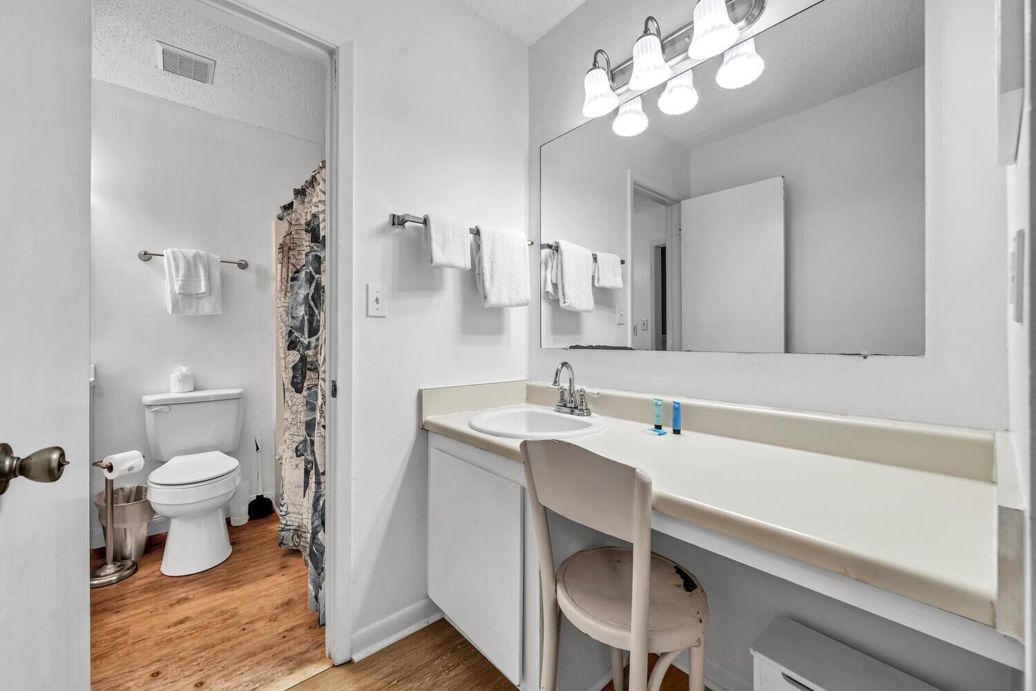 A bathroom with a toilet, sink, and mirror.