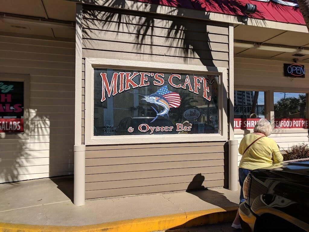 A storefront with a sign reading "Mike's Cafe & Oyster Bar" and a partial view of a sign for "Gulf Shrimp Seafood Pot Pie."