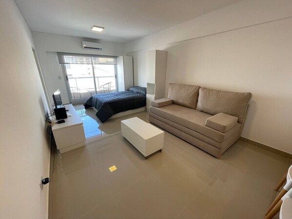 A modern bedroom with a bed, a sofa, a desk, and a window.