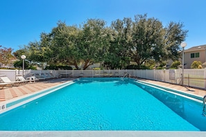 A rectangular swimming pool with a tiled deck, lounge chairs, and a fence. - Beach Dream (Miramar Beach)