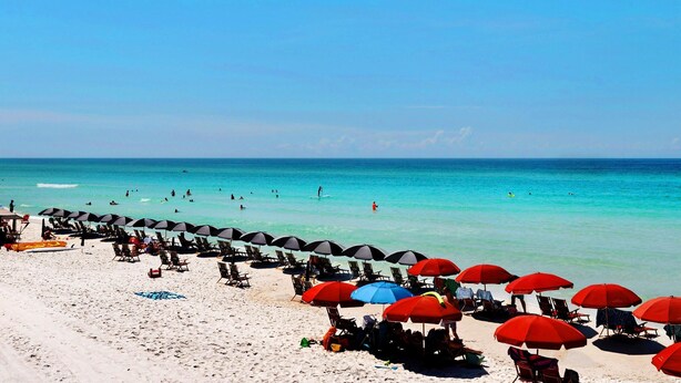 A beach with rows of sun umbrellas and lounge chairs, a clear blue sky, and the ocean in the background. - Redfish Village M1222 (Santa Rosa Beach)