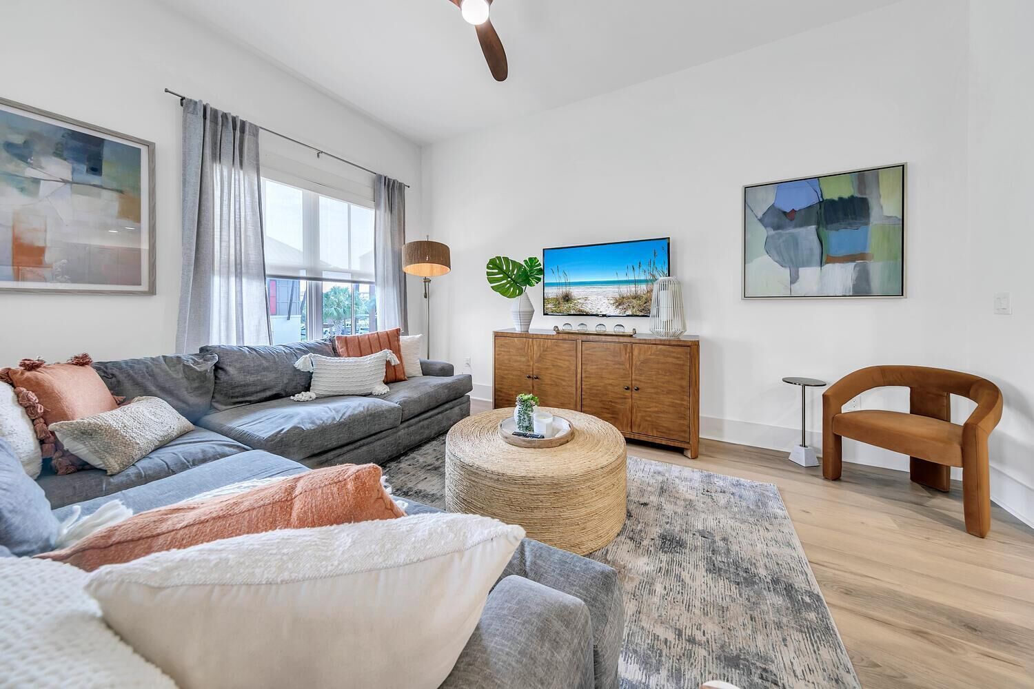 A modern living room with a grey sofa, a round coffee table, a wooden cabinet, and a TV on a stand.