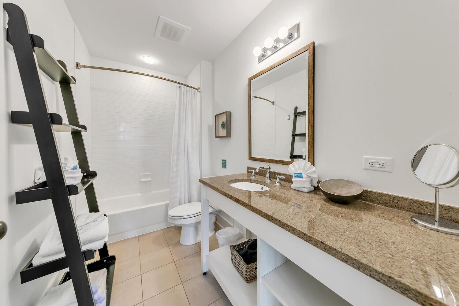 A bathroom with a bathtub, toilet, sink, and a large mirror.