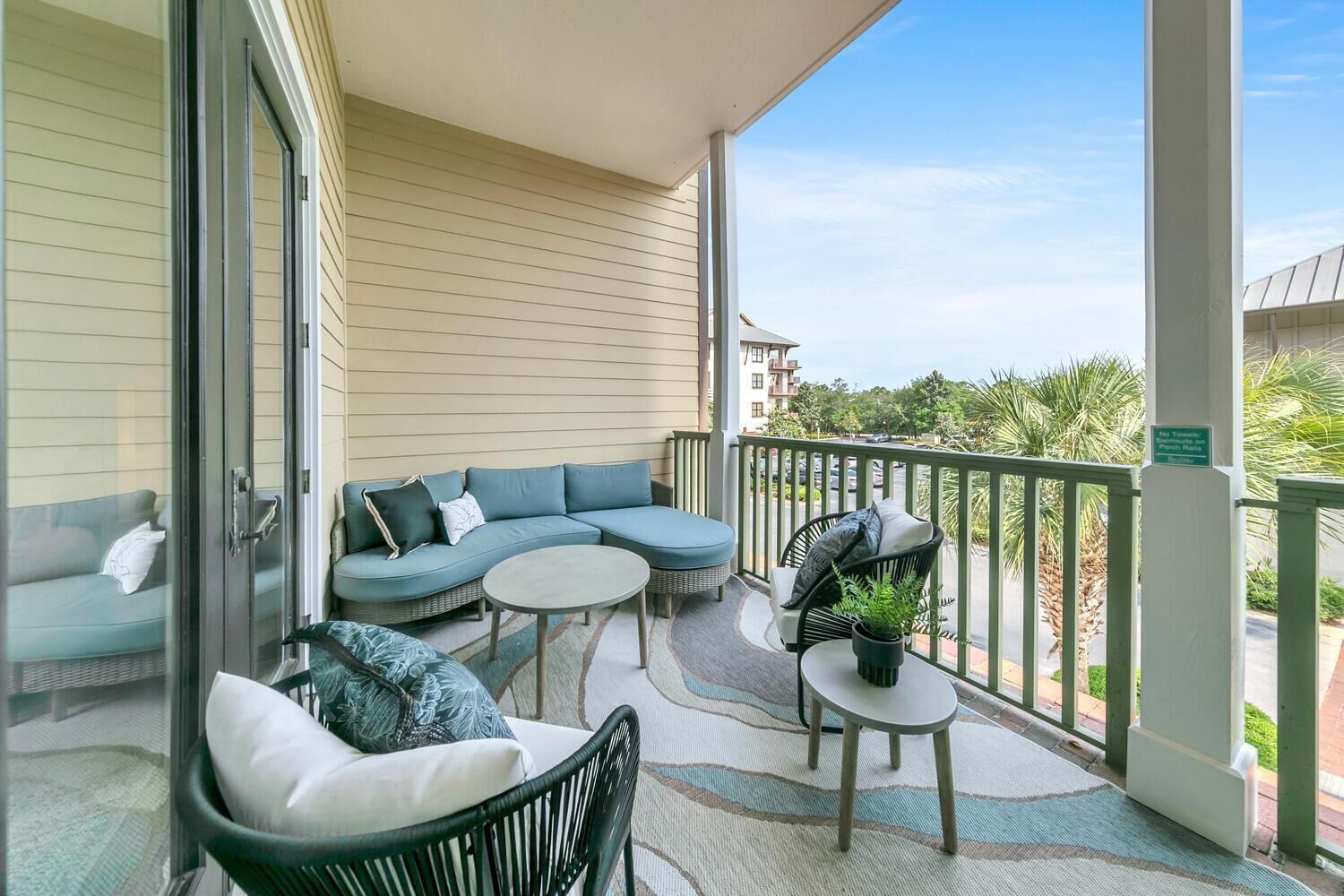 A balcony with a sectional sofa, two chairs, a small table, and a potted plant.